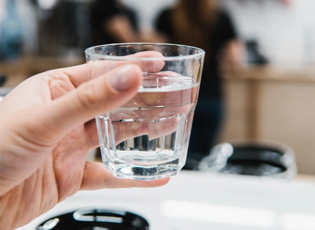 Hand holding glass of water at dental office desk with blurred background