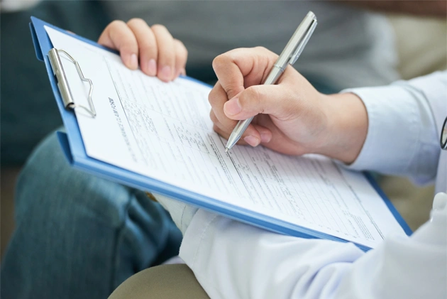 Person holding clipboard writing on dental form or document with pen