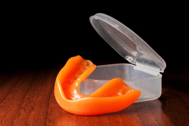 Orange peel curling from clear container on wooden surface, dental health concept.