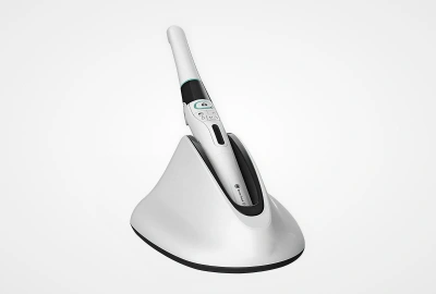 Dental curing light with white and black handle on cone-shaped base against white background.