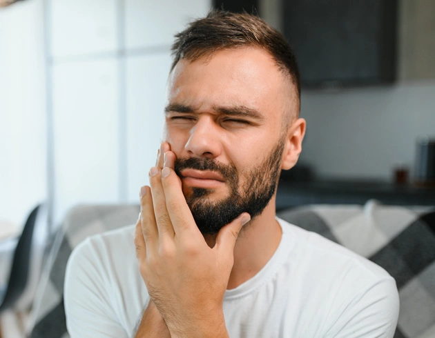 Man touching jaw in pain, dental office setting, Spring View Dental.